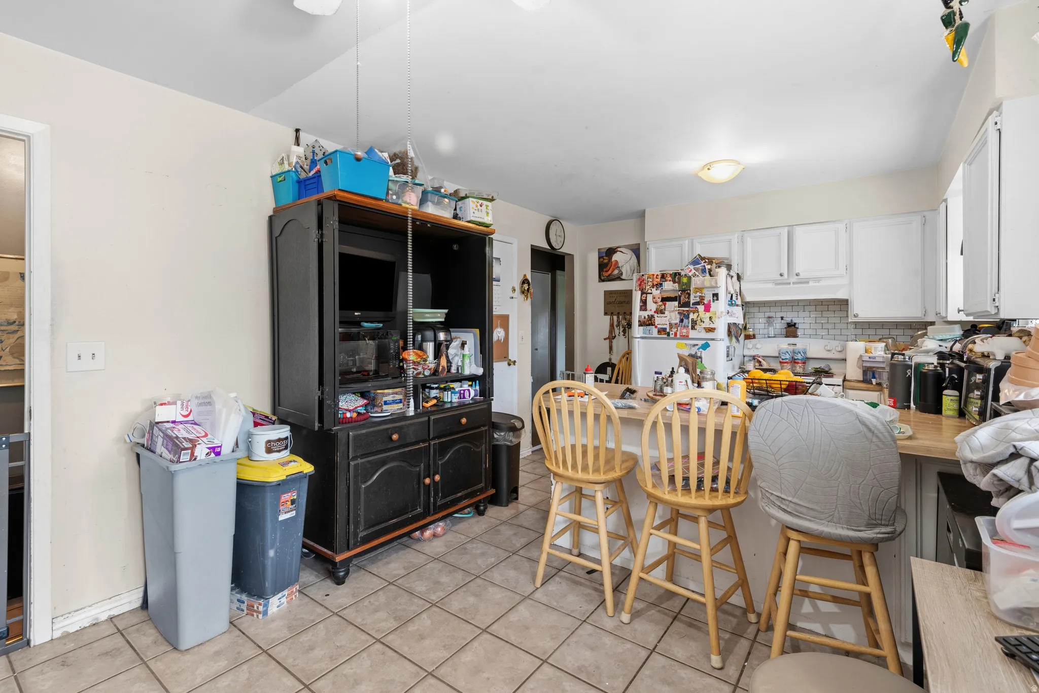 Kitchen featuring tile flooring, white cabinetry, a built-in breakfast bar, and a white subway tile backsplash