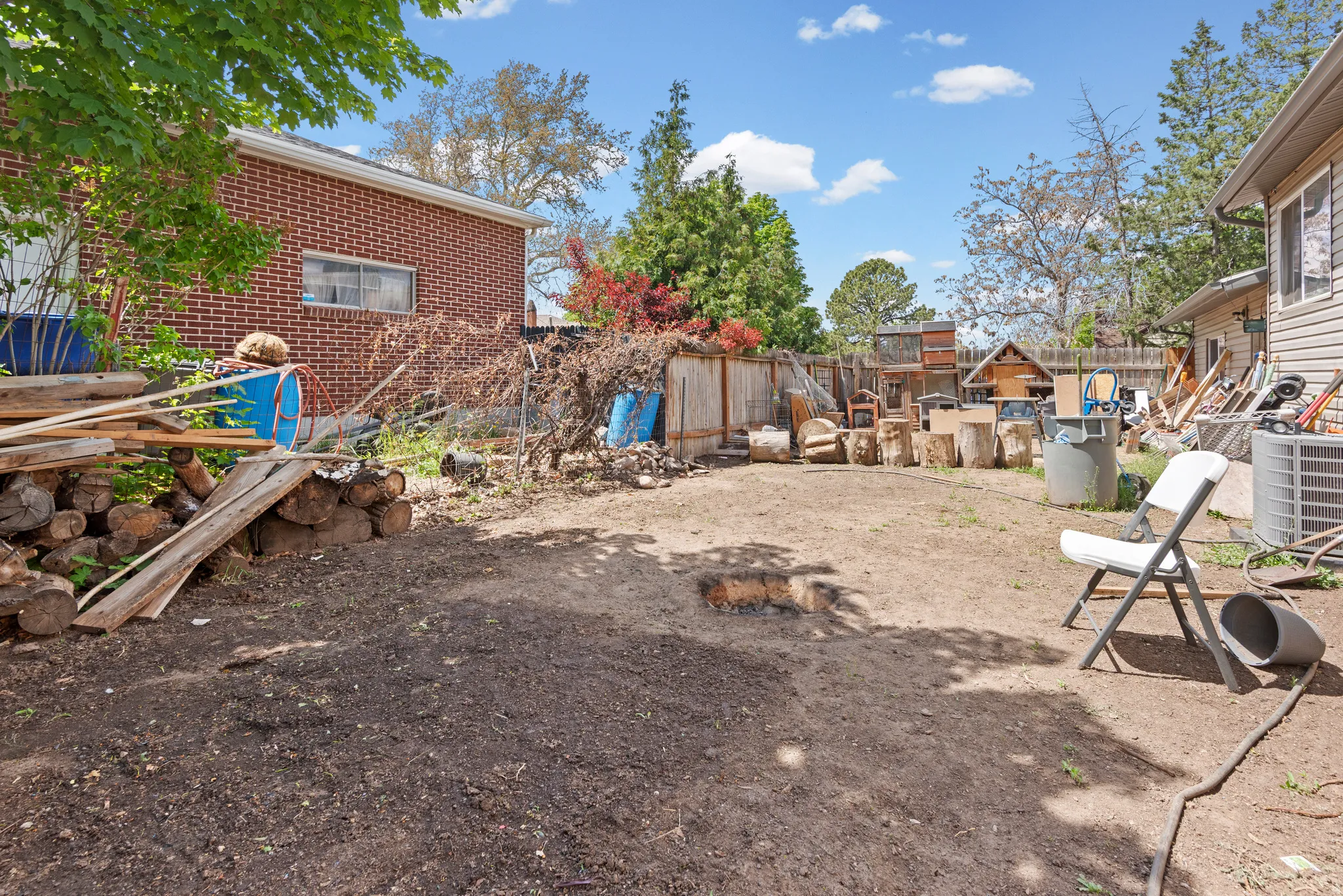 Expansive rear yard featuring a brick-sided structure, wood fencing, and mature perimeter trees