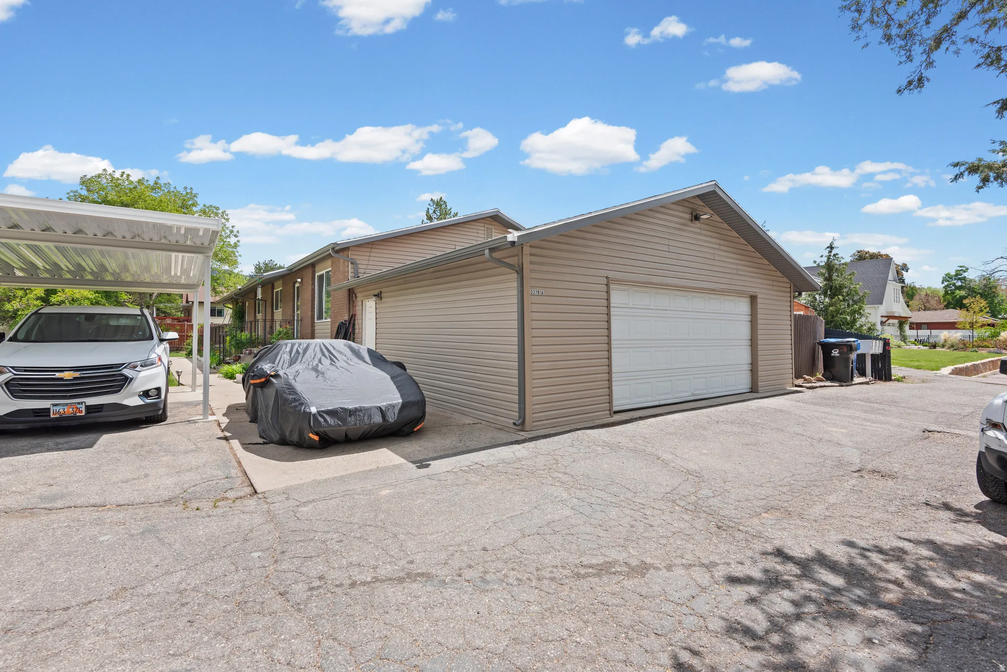 Exterior featuring a two-car garage with a white overhead door, an attached carport, and durable horizontal siding