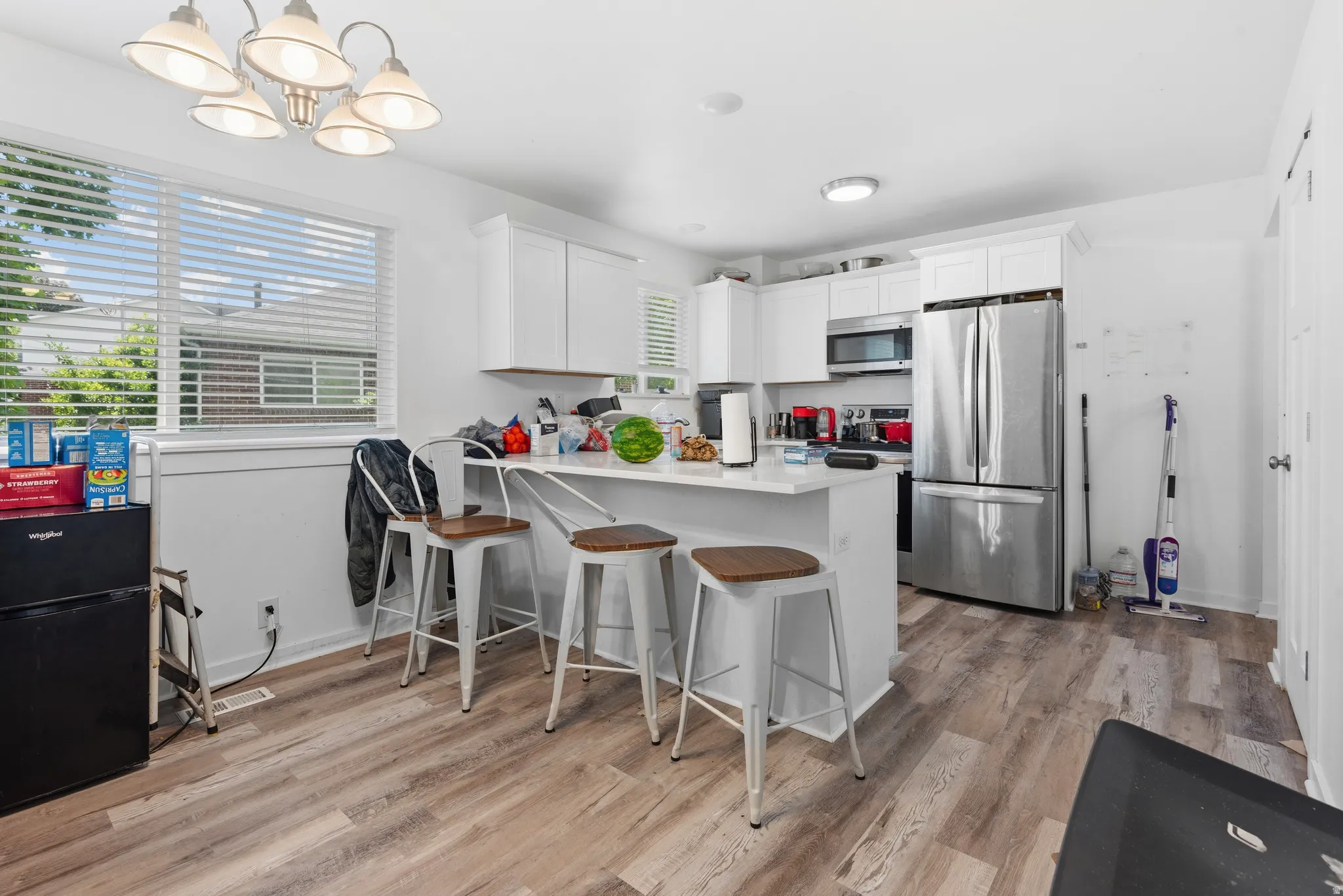 Contemporary kitchen featuring white cabinetry, a white countertop island with seating, and stainless steel appliances