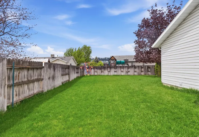 Expansive grassy yard with a wooden privacy fence