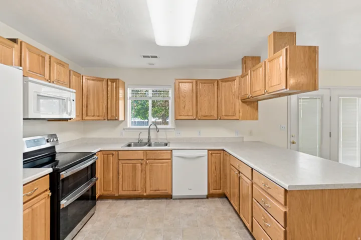Kitchen featuring light wood cabinetry, a double basin sink, and a window above