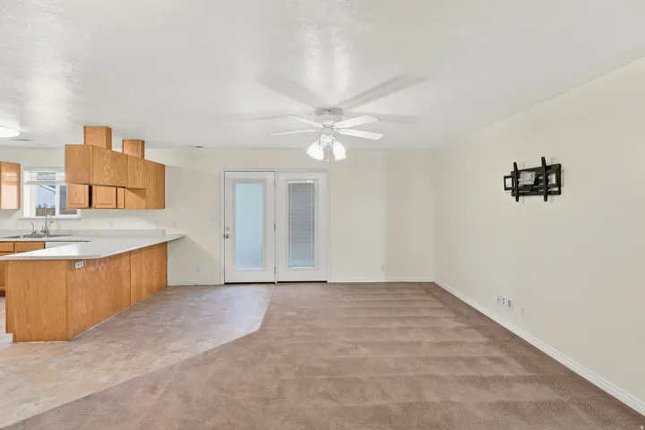 Open-concept living area featuring light-toned walls and a ceiling fan with integrated lighting