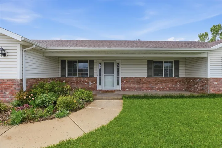 Ranch-style residence featuring white vinyl siding and brick wainscoting