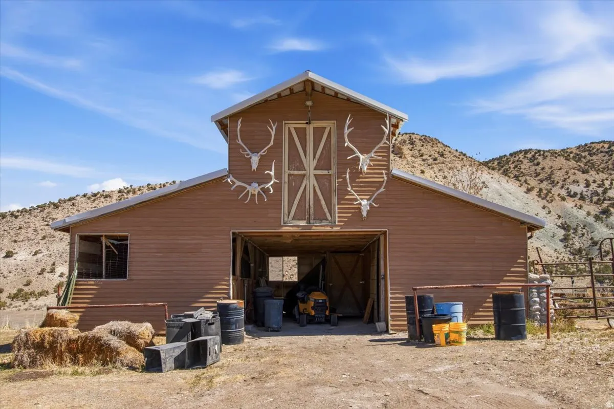 Brown siding barn structure with a prominent A-frame roof and large double barn doors on the upper level