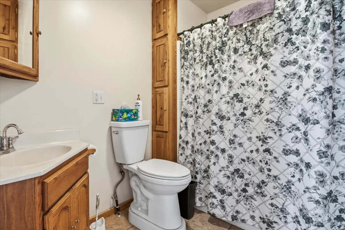 Bathroom featuring a white toilet, integrated sink with chrome faucet, wood-finish vanity with cabinet storage, and tall built-in wood-finish storage cabinetry