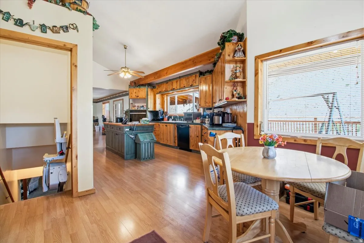 Open-concept kitchen and dining area featuring wood-finish flooring, natural wood cabinetry, a central island with integrated storage, and a ceiling fan