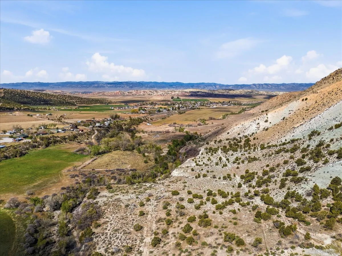 Expansive undeveloped land featuring a varied topography including sloped terrain, scattered low-lying vegetation, and distant agricultural fields