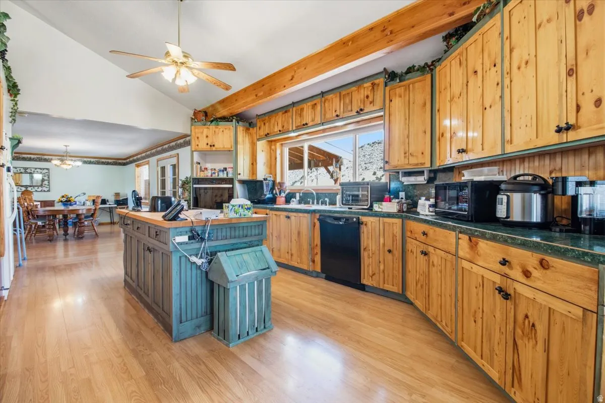 Spacious kitchen featuring natural wood cabinetry, wood-finish flooring, a central island, and an integrated dishwasher