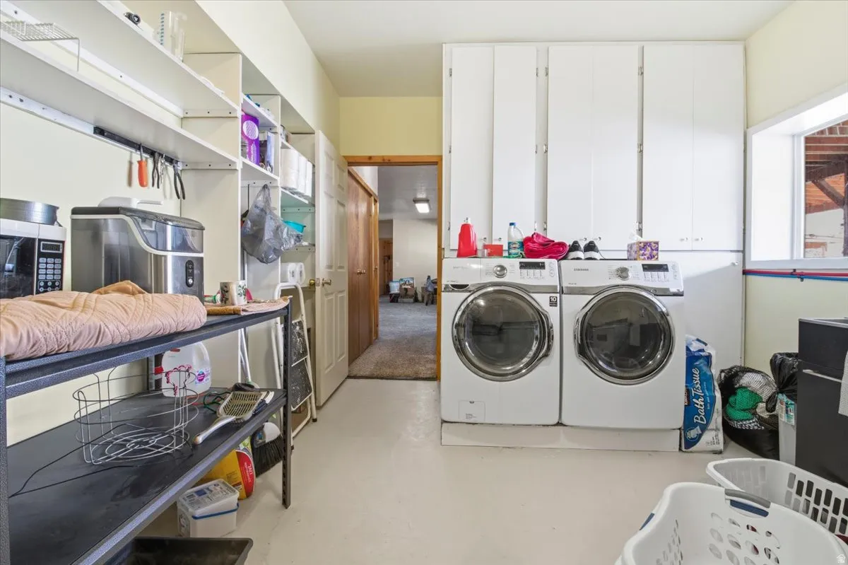 Dedicated laundry space featuring a side-by-side washer and dryer set, white cabinetry, open shelving, a built-in countertop, and a window providing natural light