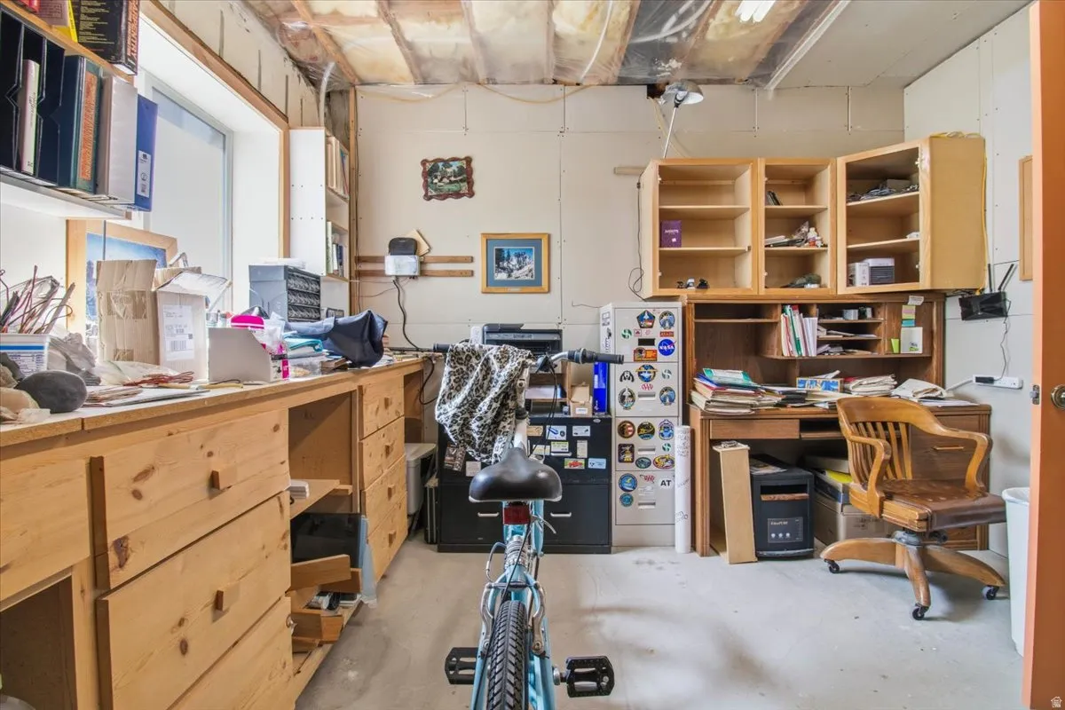 Workroom featuring a window, built-in wooden cabinetry, a built-in wooden desk, and overhead lighting