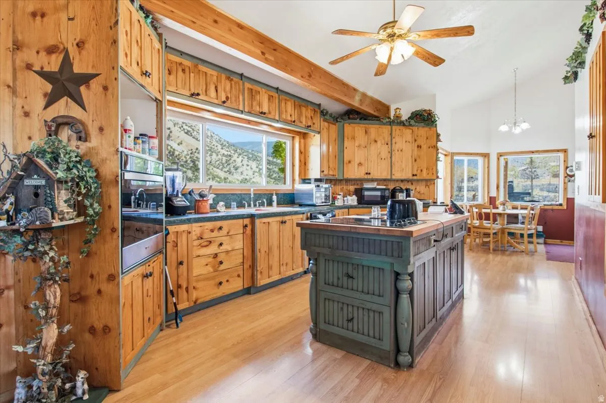 Kitchen featuring wood-finish cabinetry, a central island with a wood-finish countertop, stainless steel double wall ovens, wood-finish flooring, and exposed wood beams