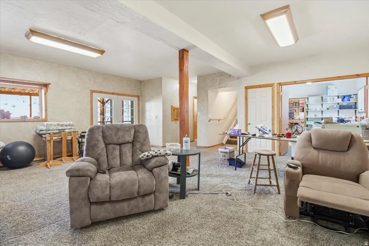 Versatile room featuring textured wall finishes, carpeted flooring, and exposed wood structural elements