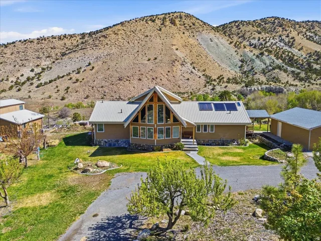 Gable-front home featuring a metal roof, stone facade, and expansive windows