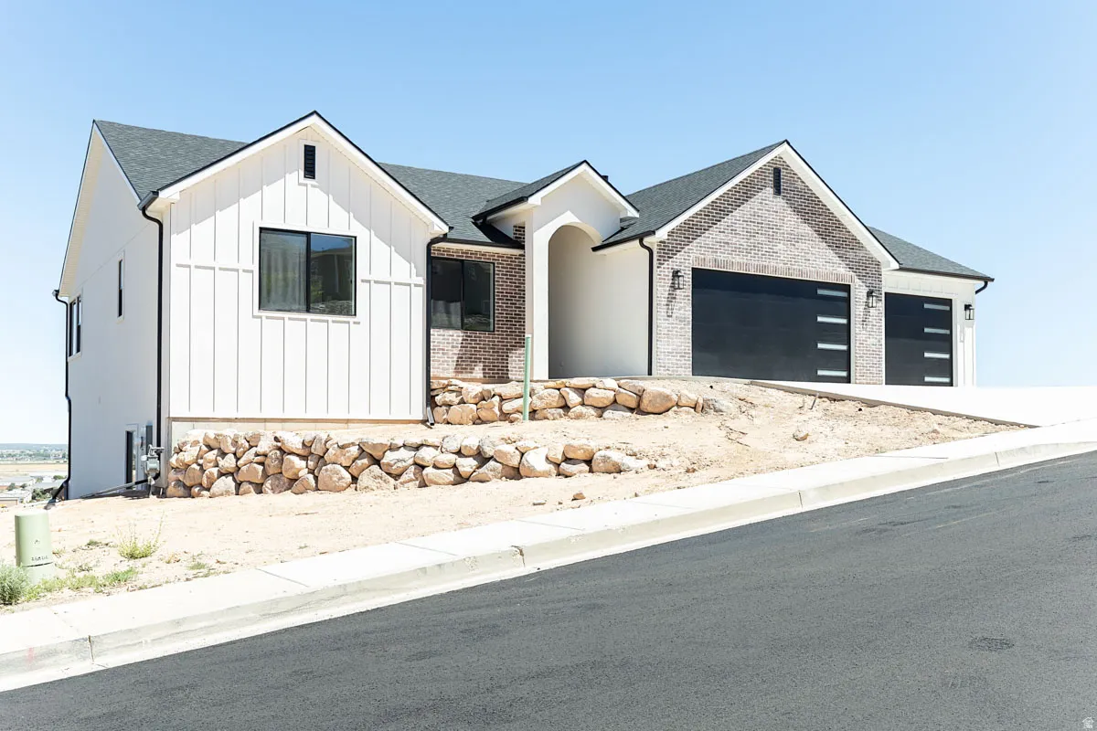 Contemporary residence featuring a board-and-batten facade, light-toned brick accents, black-framed windows, and a black shingle roof