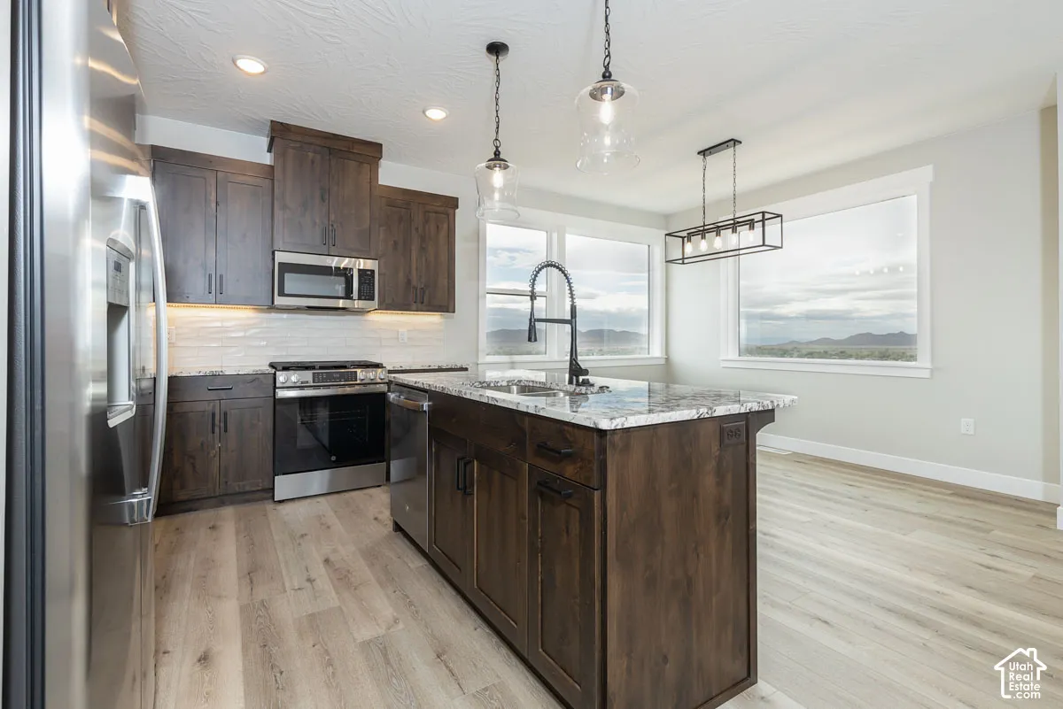 Kitchen featuring dark wood-finish cabinetry, stainless steel appliances, granite countertops, and wood-finish flooring