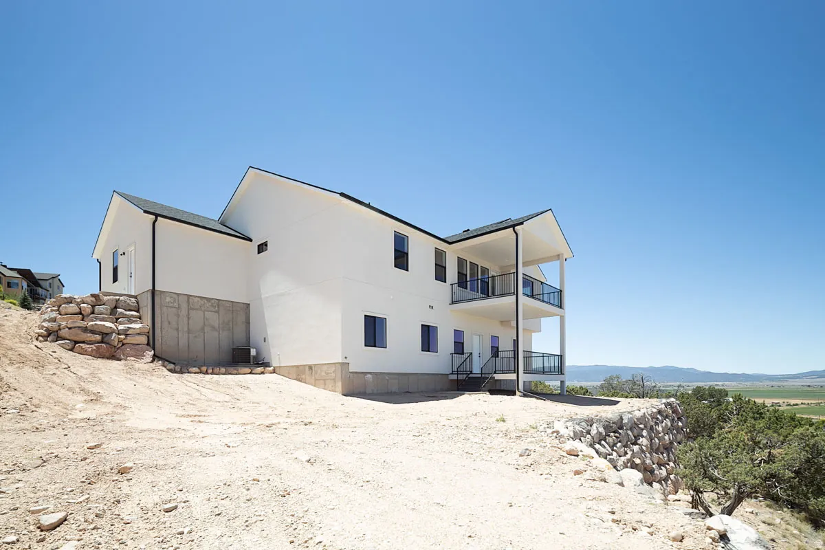 Modern white exterior featuring a two-story covered balcony with black railings and glass panels