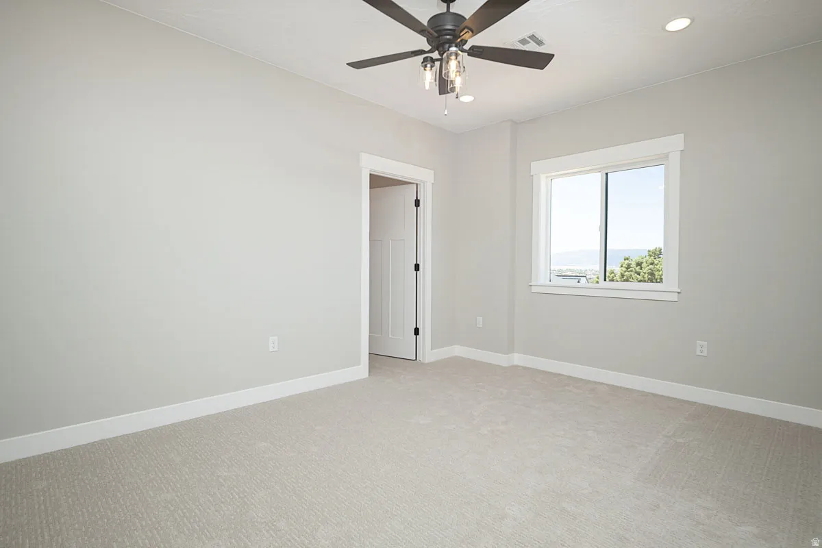 Light-filled interior space with a window, ceiling fan with integrated lighting, recessed lighting, neutral carpeting, and white baseboards