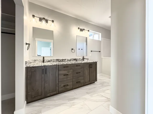 Dual vanity with dark wood-finish cabinetry, under-mount sinks, and a stone-look countertop