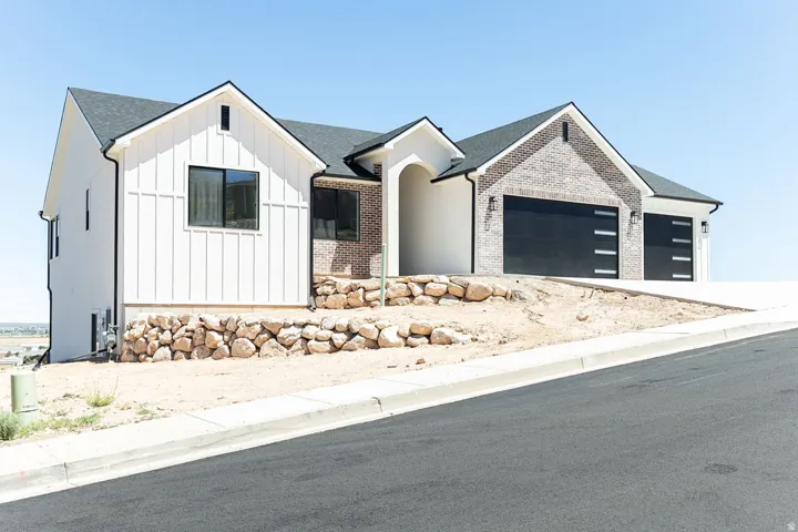 Contemporary residence featuring a board-and-batten facade, light-toned brick accents, black-framed windows, and a black shingle roof