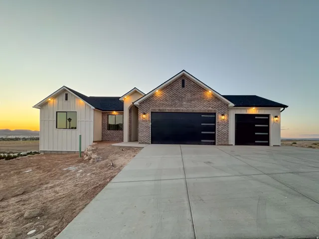 Contemporary exterior featuring board and batten siding, brick accents, and a dark shingle roof