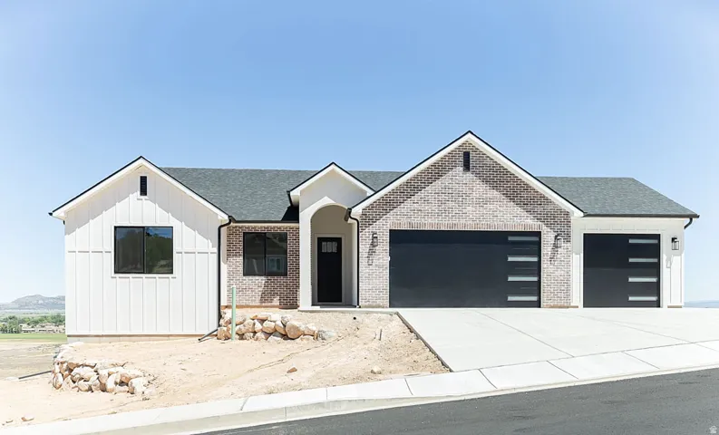 Modern exterior featuring white board and batten siding, light-colored brick accents, dark-framed windows, and a dark asphalt shingle roof