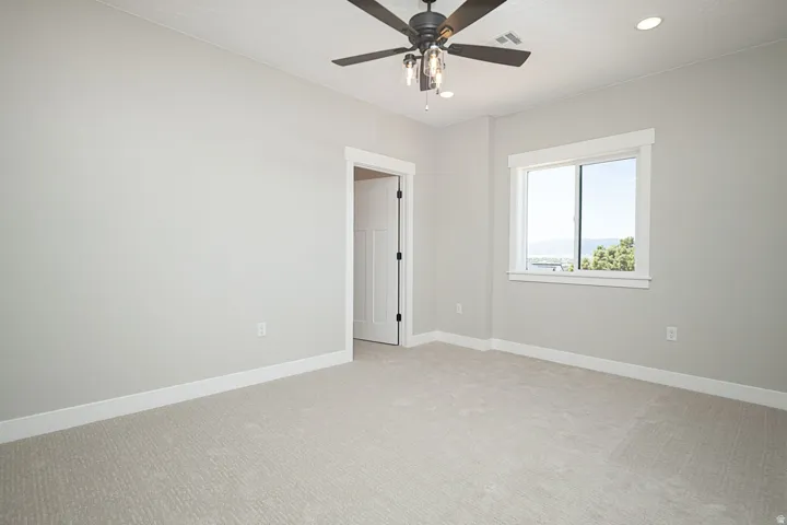 Light-filled interior space with a window, ceiling fan with integrated lighting, recessed lighting, neutral carpeting, and white baseboards