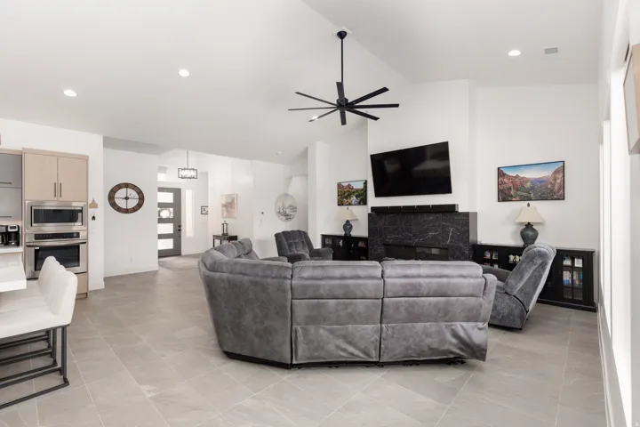 Open concept living area featuring vaulted ceilings, a modern black ceiling fan, and recessed lighting
