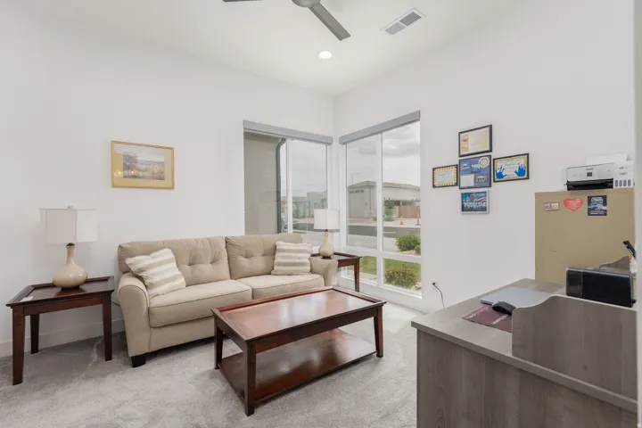 Room featuring light gray carpeting, crisp white walls, and an integrated ceiling fan
