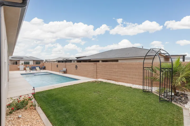 Backyard oasis featuring a rectangular swimming pool, concrete patio, and a manicured lawn