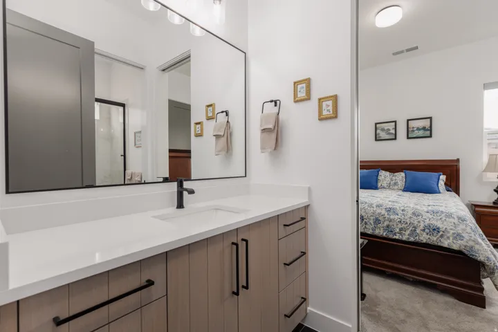Bathroom vanity featuring a single integrated sink, a white countertop, and light wood-finish cabinetry with black hardware