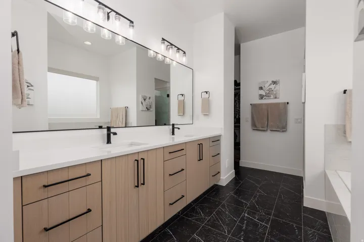 Dual vanity with light wood-finish cabinetry, quartz countertops, and matte black hardware