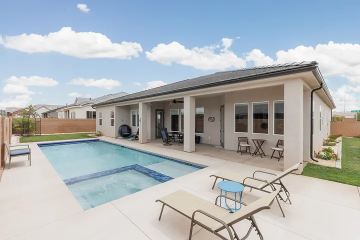Backyard oasis featuring an in-ground swimming pool with an integrated spa, extensive concrete patio, and a covered patio area