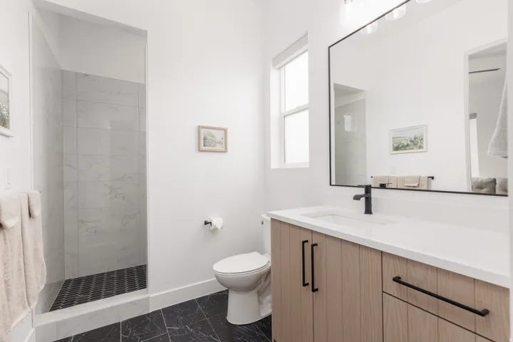 Contemporary bathroom featuring a light wood-finish vanity with an integrated sink and matte black fixtures
