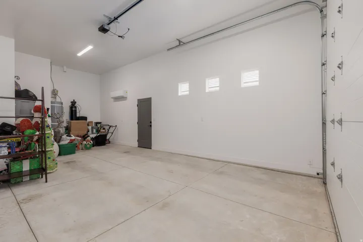 Spacious garage featuring a concrete floor, white walls, and a white paneled garage door