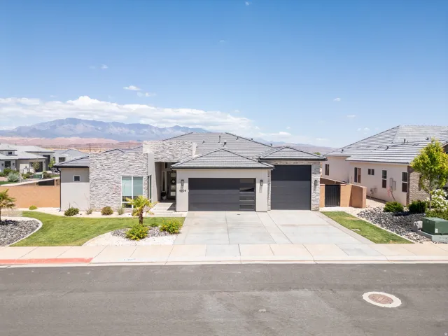 Contemporary stucco and stone-clad exterior with a dark tile roof
