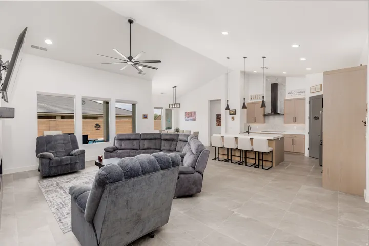 Open-concept living space featuring vaulted ceilings, recessed lighting, and large format tile flooring