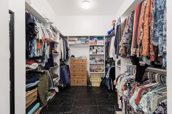 Walk-in closet with dark tile flooring and white built-in shelving