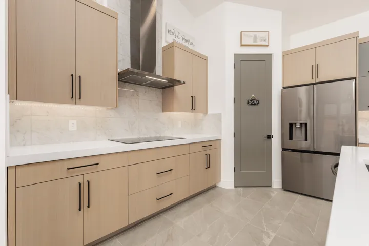 Modern kitchen featuring light wood-finish cabinetry, stainless steel appliances, and a sleek cooktop