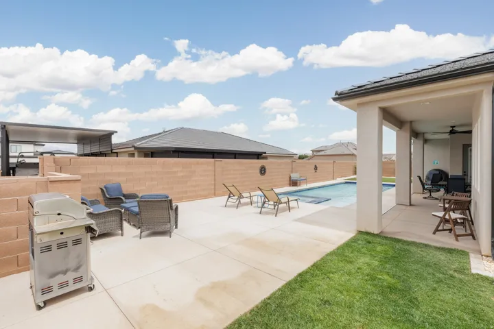 Outdoor living space featuring a rectangular swimming pool, concrete patio, covered patio area, and a privacy block wall