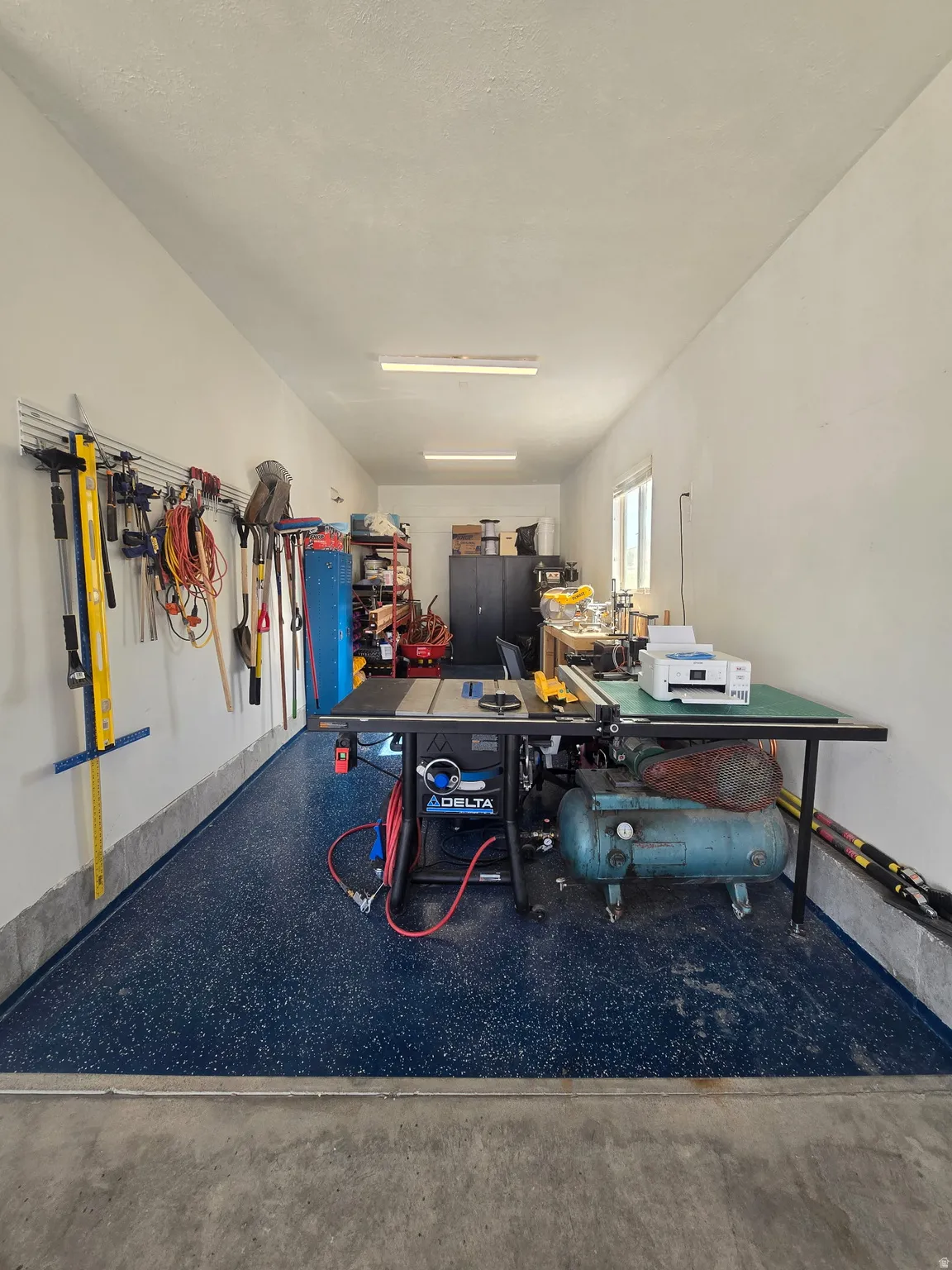 Spacious garage featuring a blue speckled floor, white walls, and bright overhead lighting