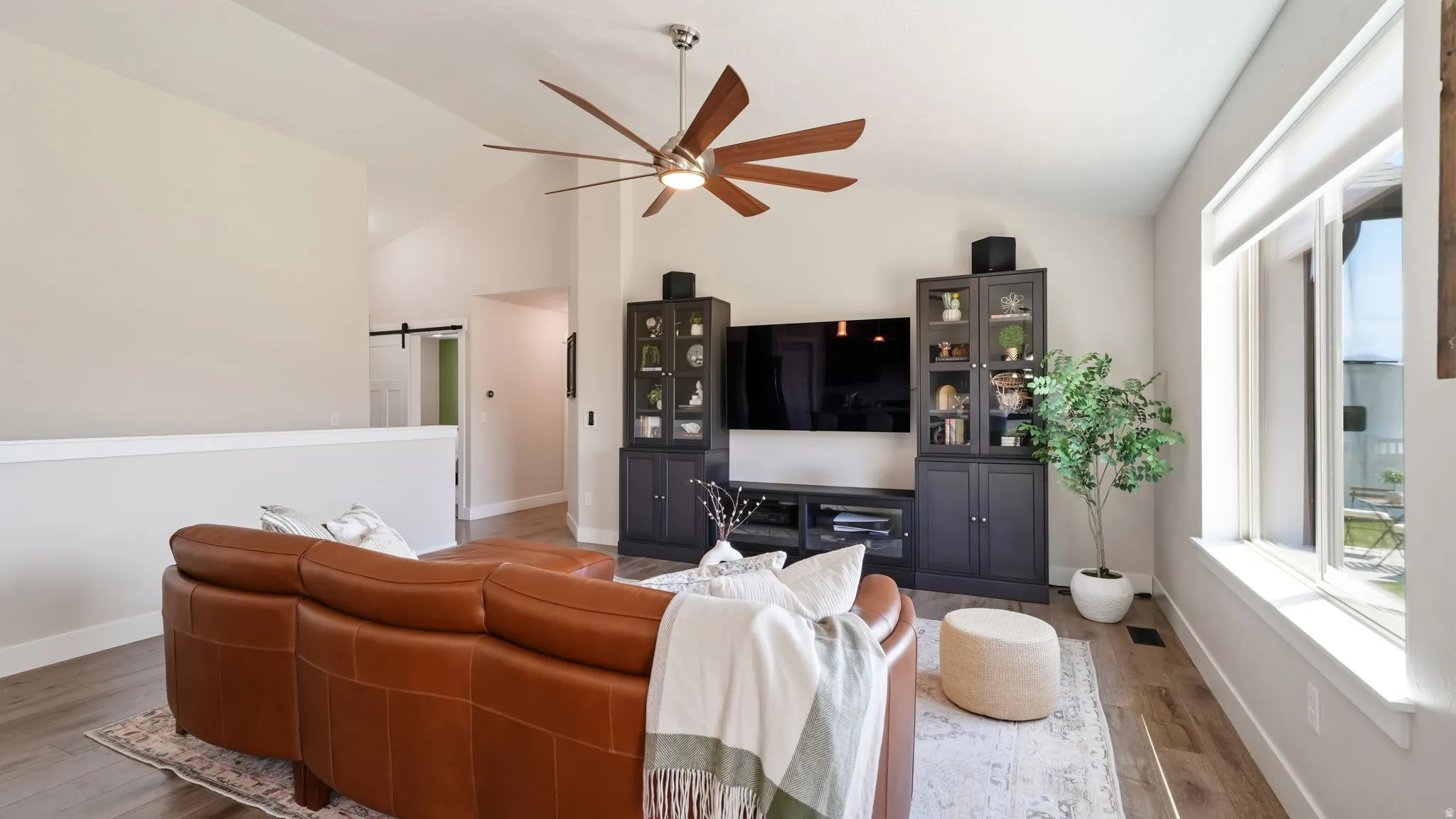 Spacious living area featuring vaulted ceilings, wood-finish flooring, and a contemporary ceiling fan