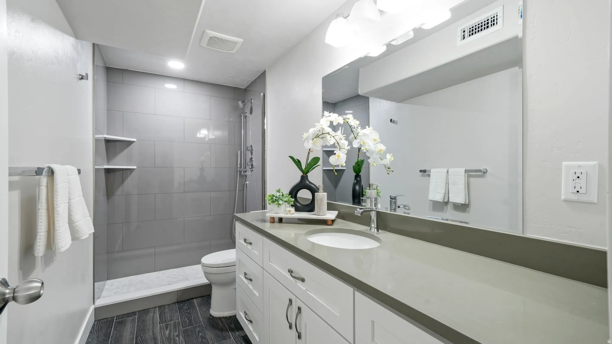 Bathroom featuring a long single vanity with an integrated sink, a gray countertop, and walk-in shower