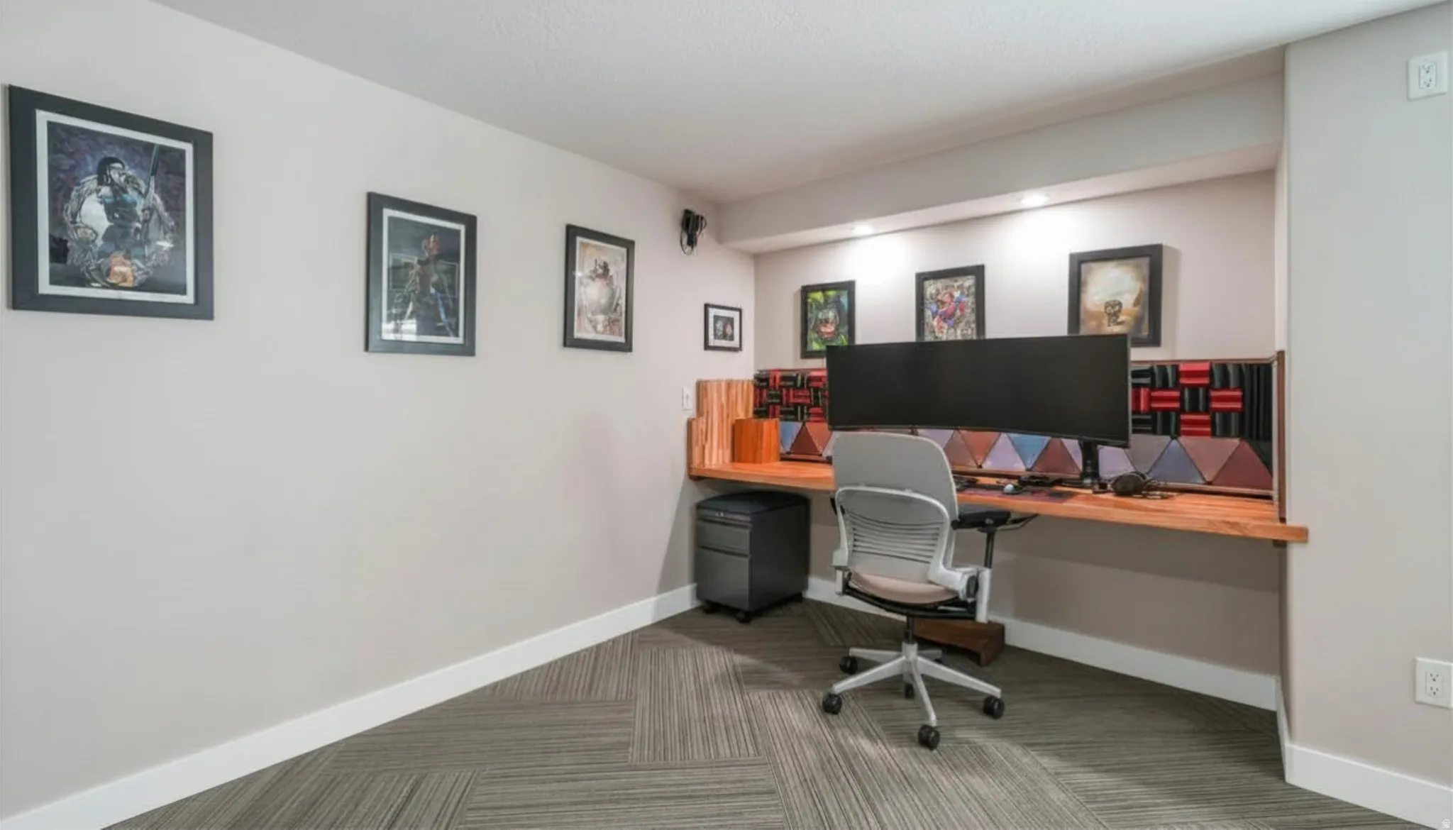 Built-in wood-finish desk with task lighting and acoustic paneling