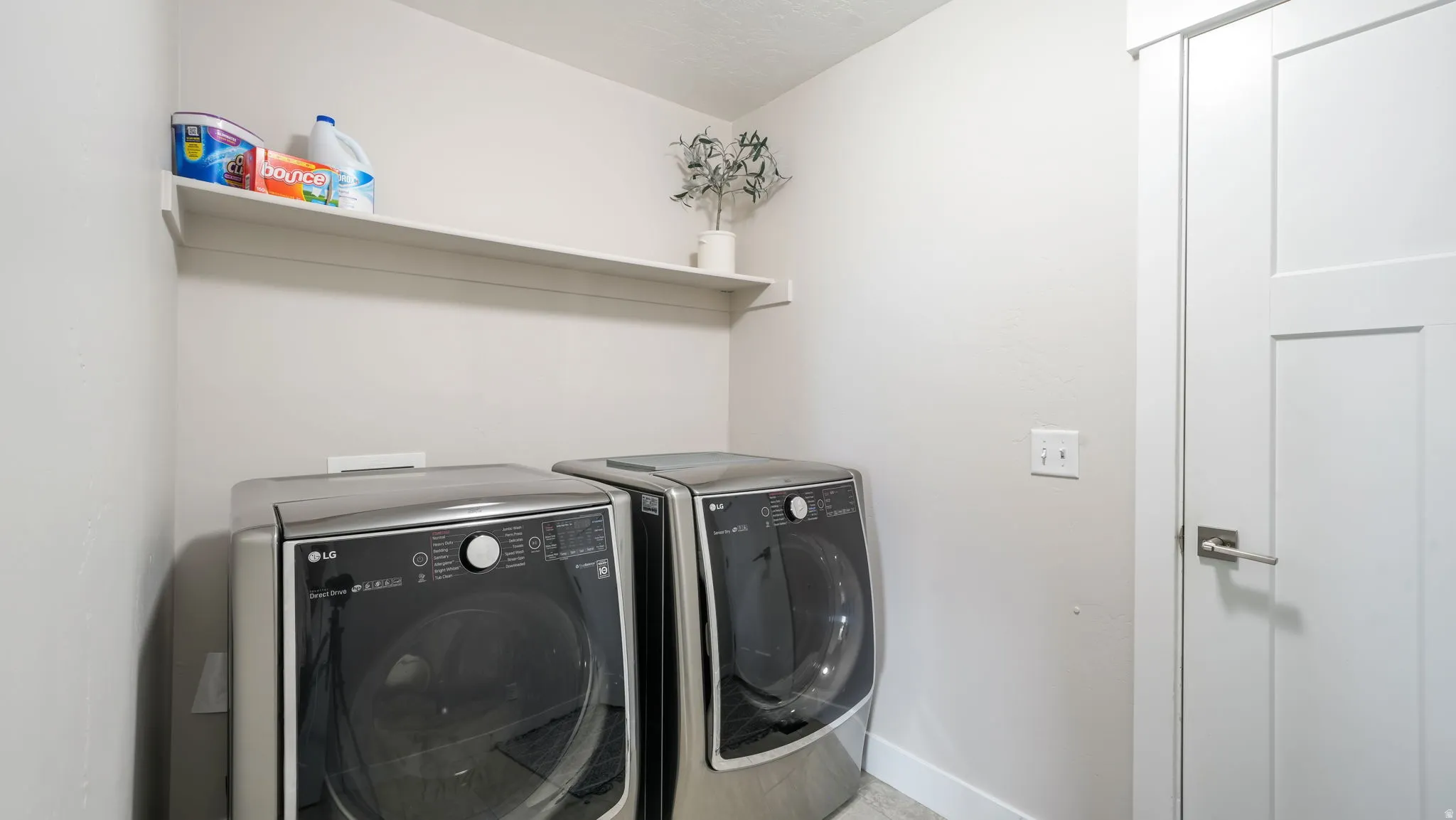 Dedicated laundry space featuring a built-in wall shelf, and white trim