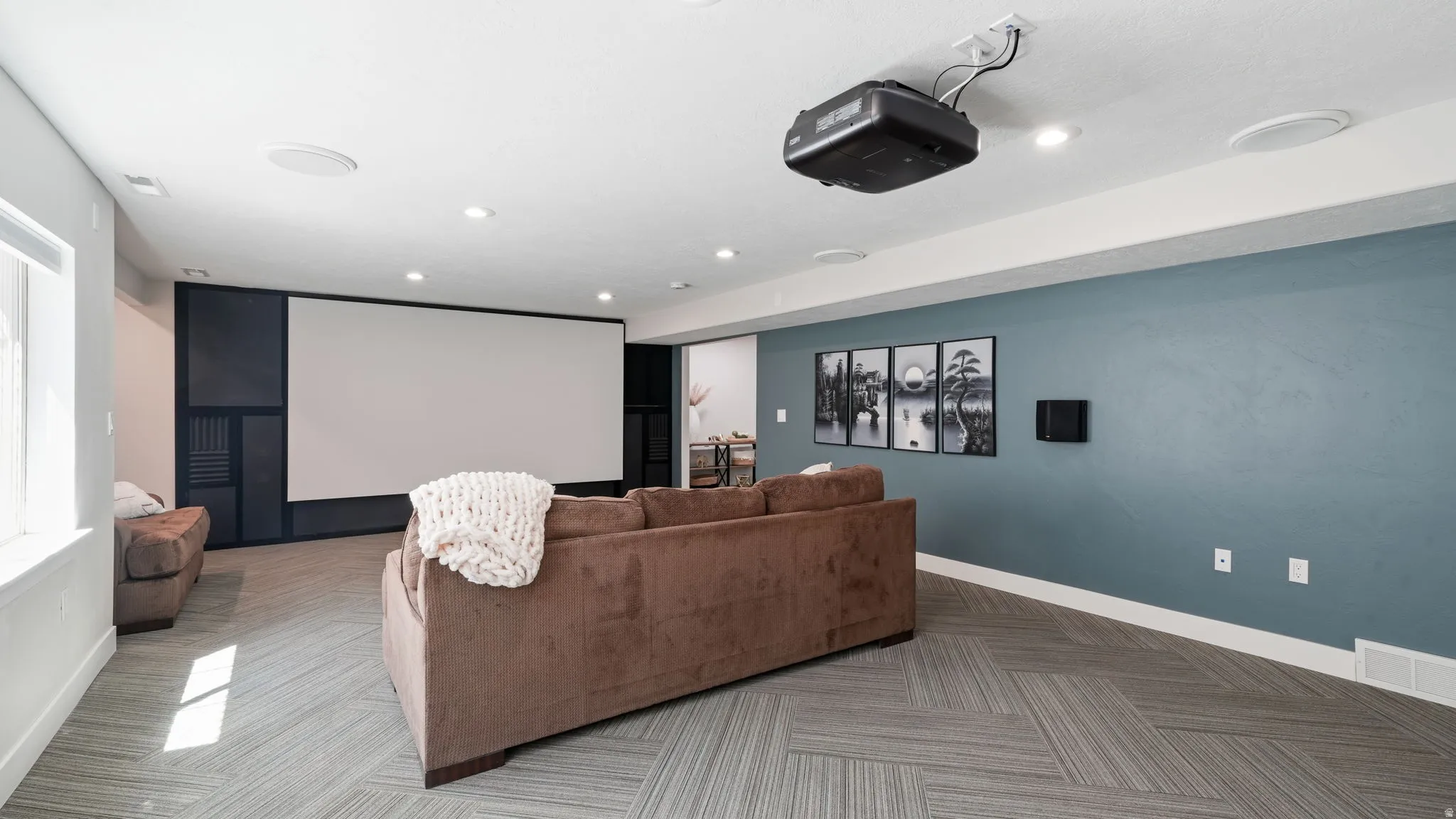 Media room featuring a large projection screen, ceiling-mounted projector, recessed lighting, and built-in ceiling speakers