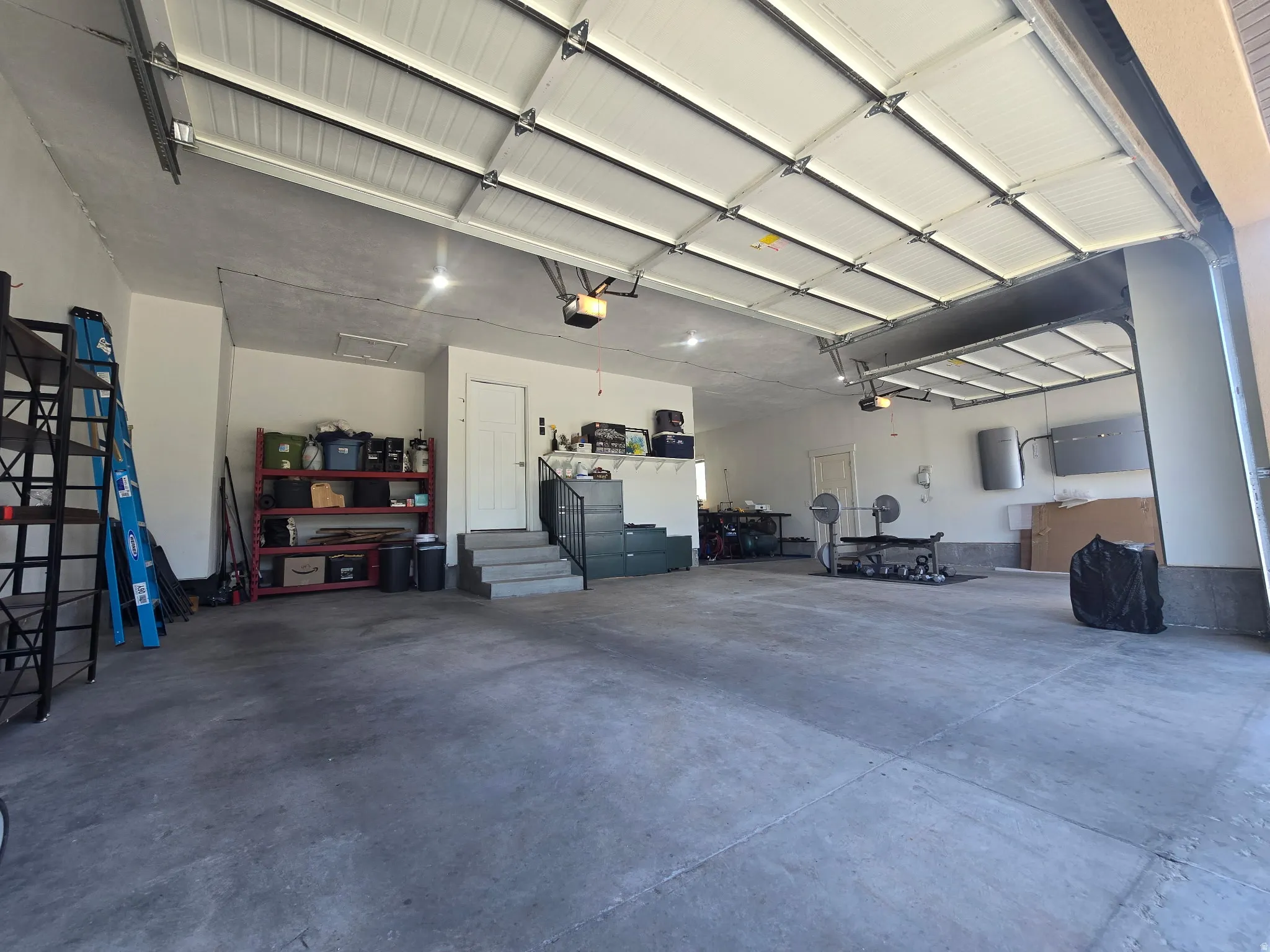 Spacious garage with two overhead doors, concrete flooring, and multiple light fixtures