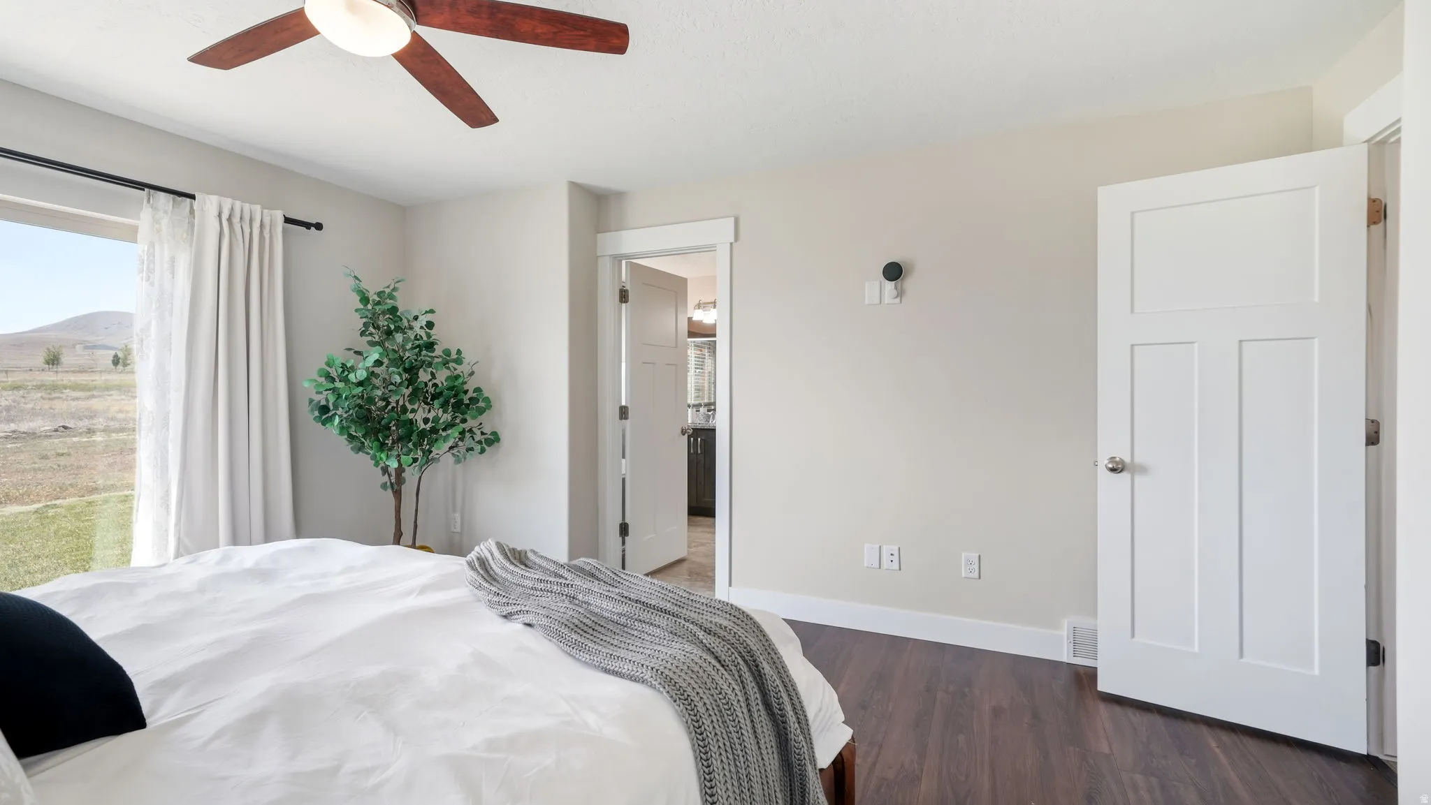 Bedroom featuring sliding door, dark wood-finish flooring, and ceiling fan
