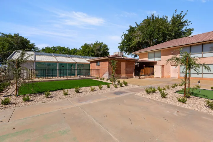 Expansive outdoor space featuring a covered, fenced pool area, concrete patio, and a putting green