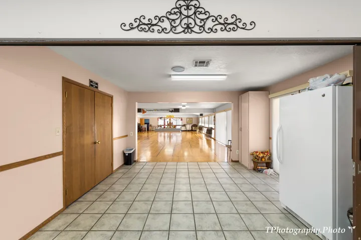 Tiled flooring leading to a spacious room with hardwood flooring